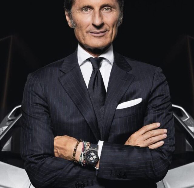 CEO da Lamborghini com um carro branco atrás.