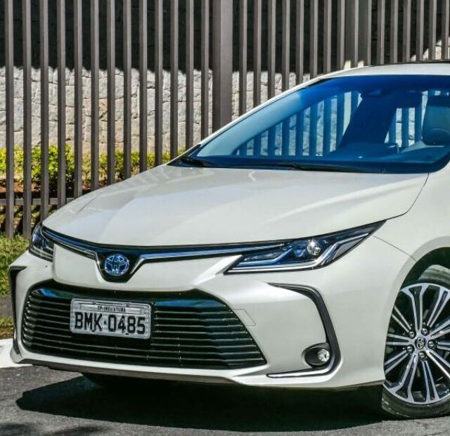 Toyota Corolla hibrido branco parado na diagonal.