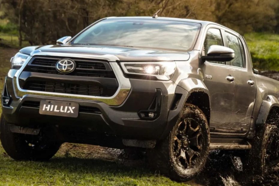 Picape Hilux cinza em velocidade na lama.