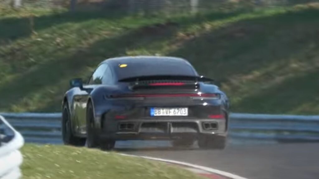 Traseira da Porsche 911 Turbo 2026 preta na pista de corrida.
