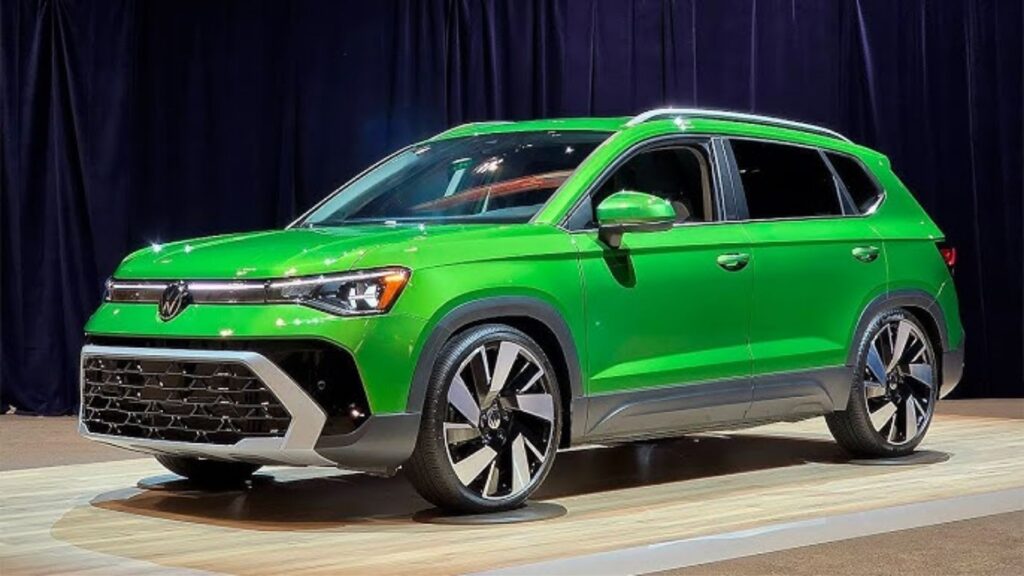 Volkswagen Taos verde parado na diagonal em uma exposição.
