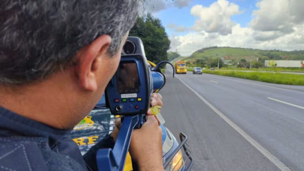 Policial com o radar portátil apontando na pista.