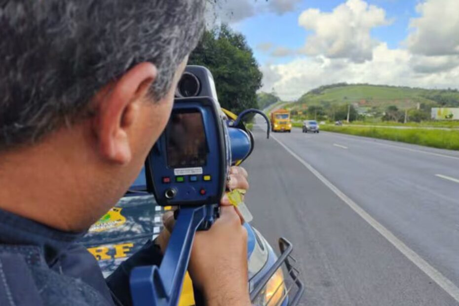 Policial com o radar portátil apontando na pista.
