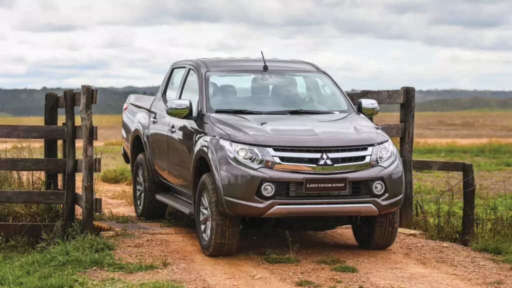 Picape da Mitsubishi cinza passando na porteira.