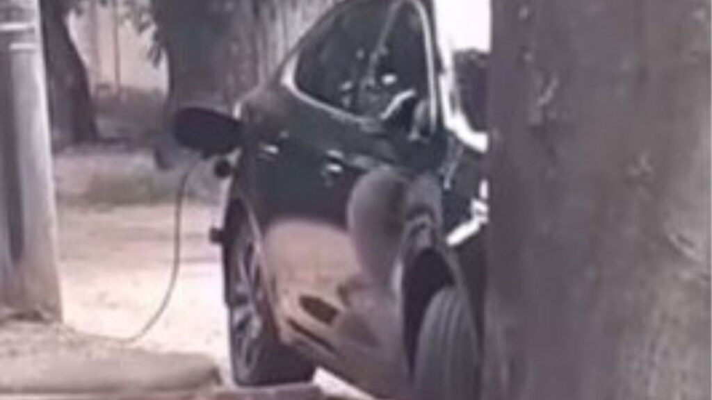 Carro preto da BYD sendo carregado por um gato que o motorista fez em um poste.