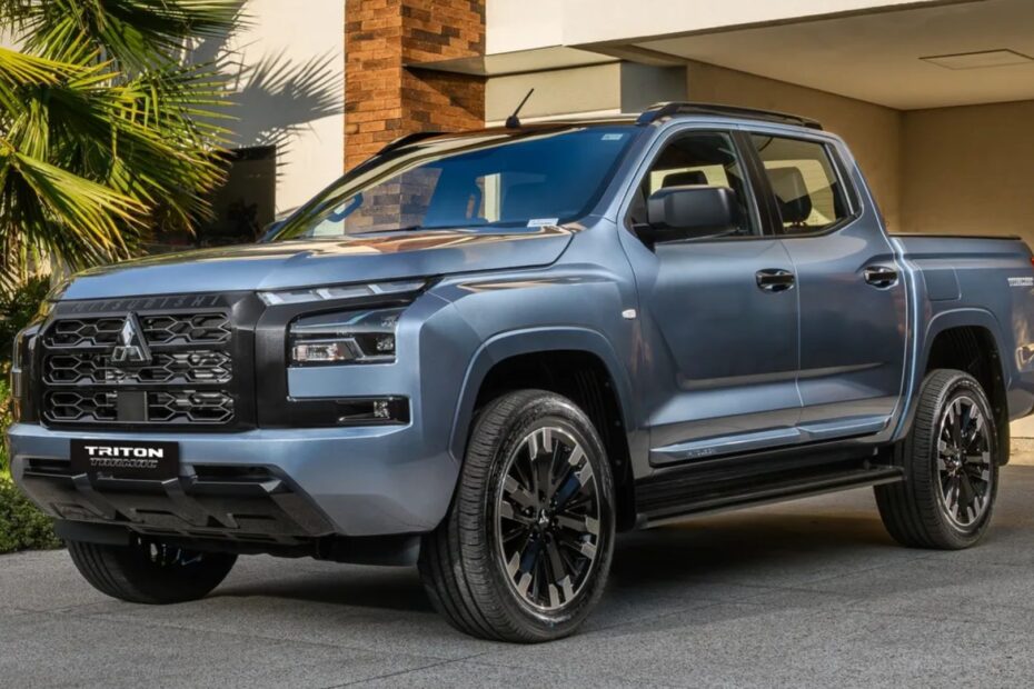 Mitsubishi Triton Tarmac azul parado na diagonal na frente de uma garagem.