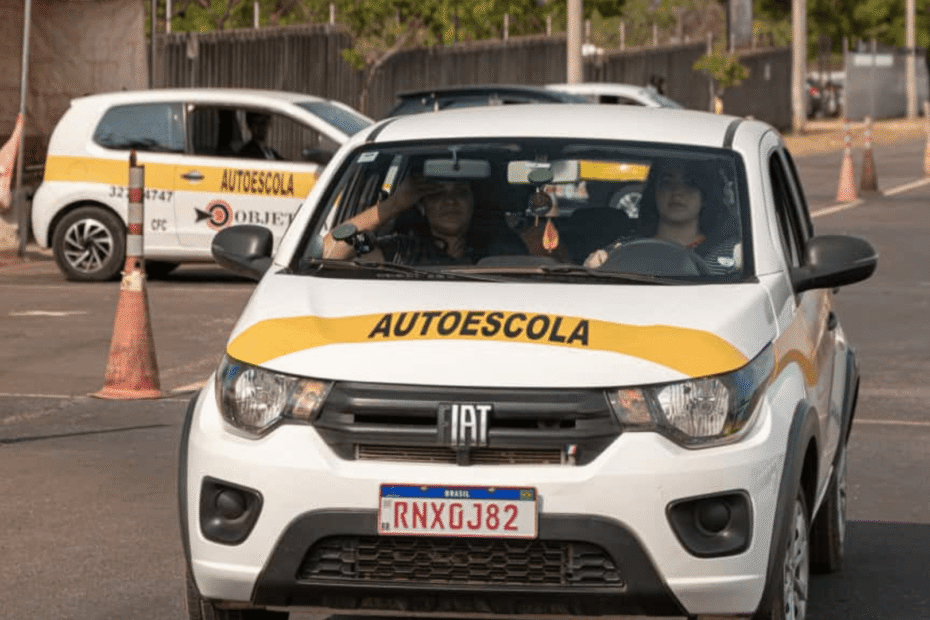 Carro branco da autoescola em movimento.