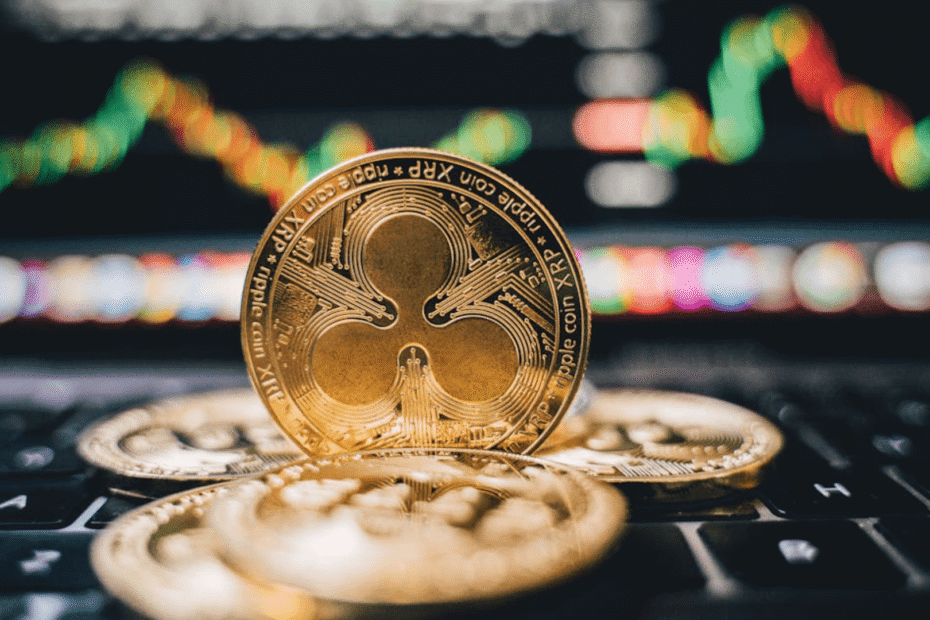 Moeda XRP dourada em cima de outras moedas em cima do teclado de um notebook.